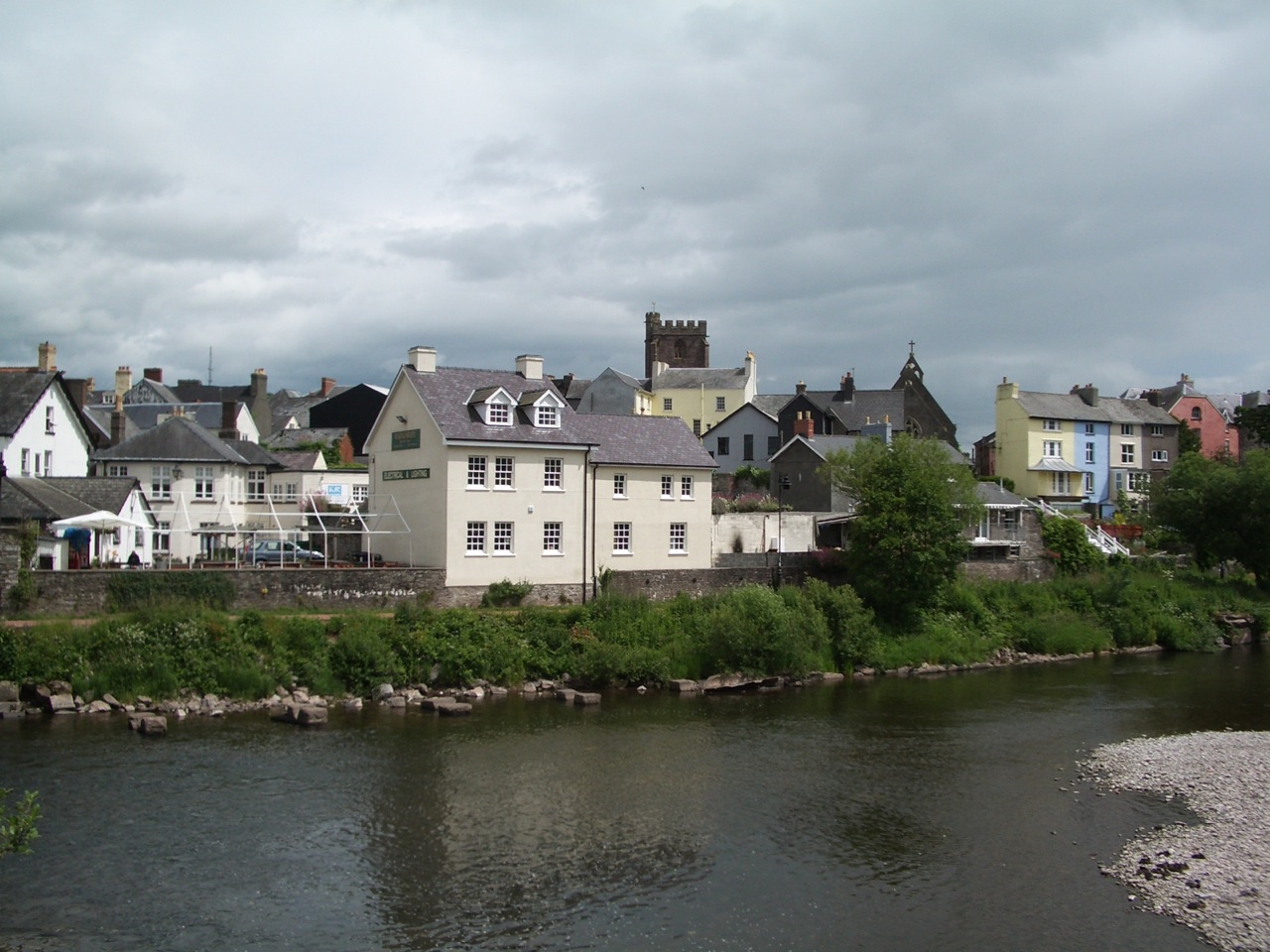 Brecon town seen from the River Usk with church spire and colourful houses