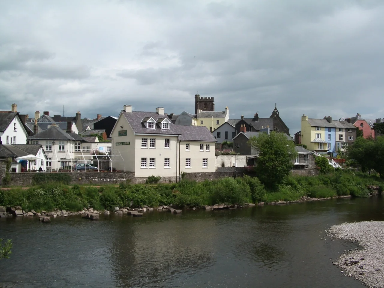 Brecon town seen from the River Usk with church spire and colourful houses