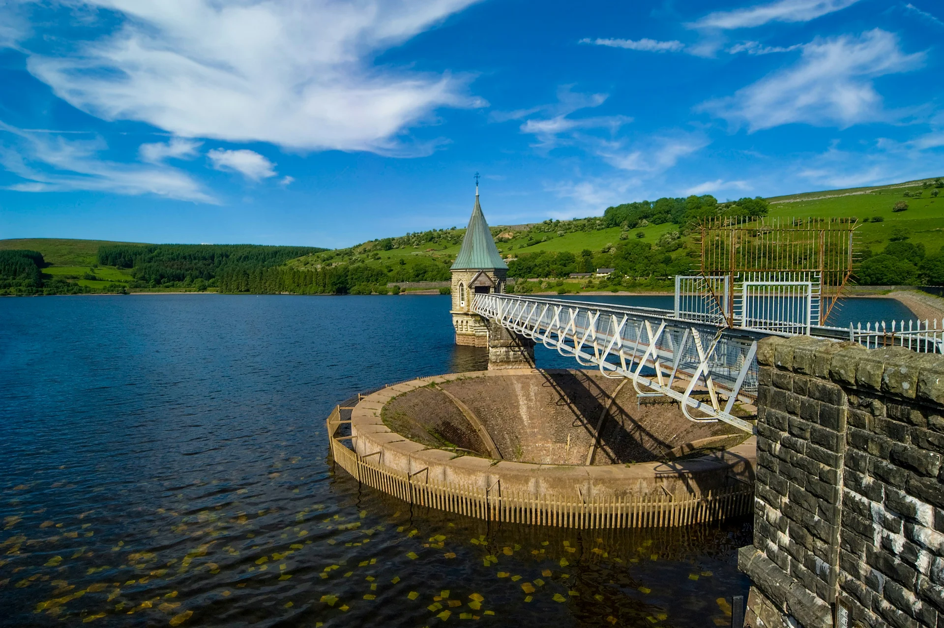 A Victorian valve tower rising from still water in the wooded Taf Fechan valley