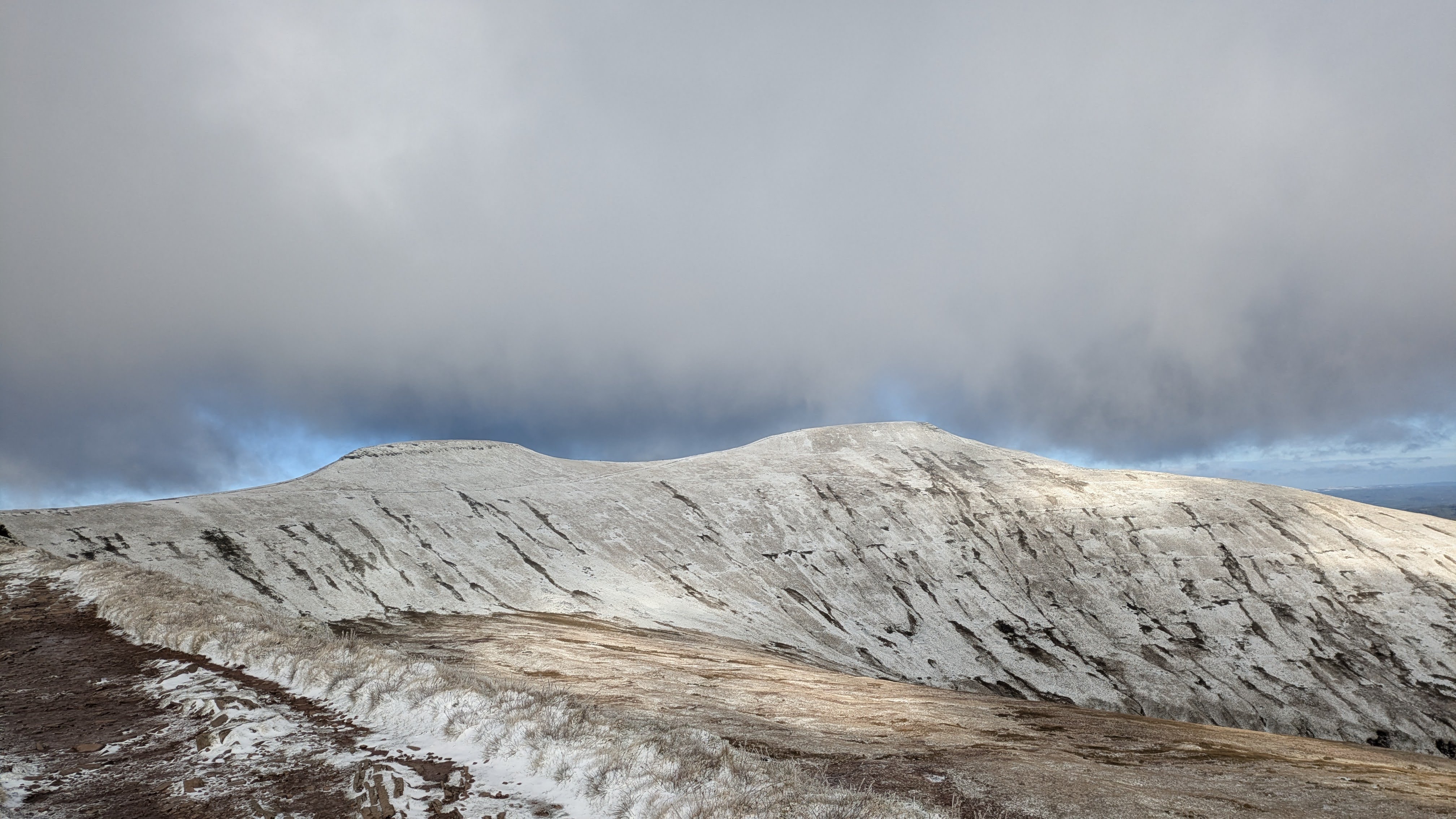 Snow-dusted Pen y Fan ridge under a dramatic winter sky