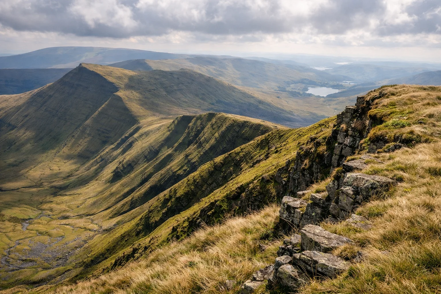 A wide grassy escarpment ridge falling away to a broad valley