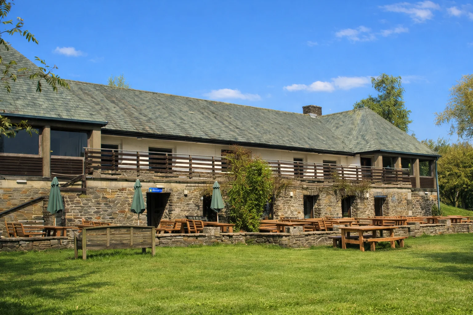 A stone visitor centre building with picnic benches on the lawn
