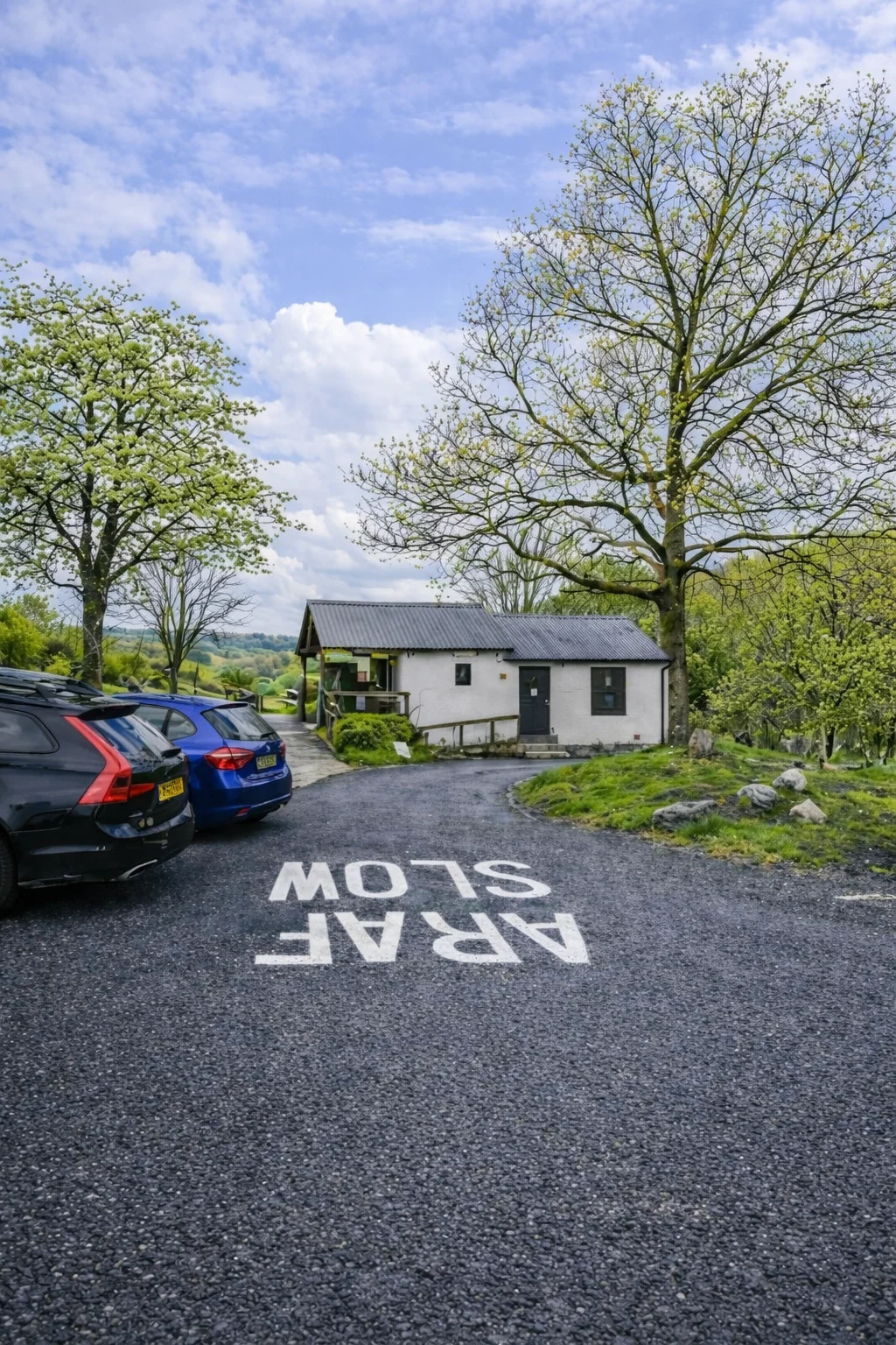 Cars parked on a small gravel car park with ARAF SLOW painted on the tarmac