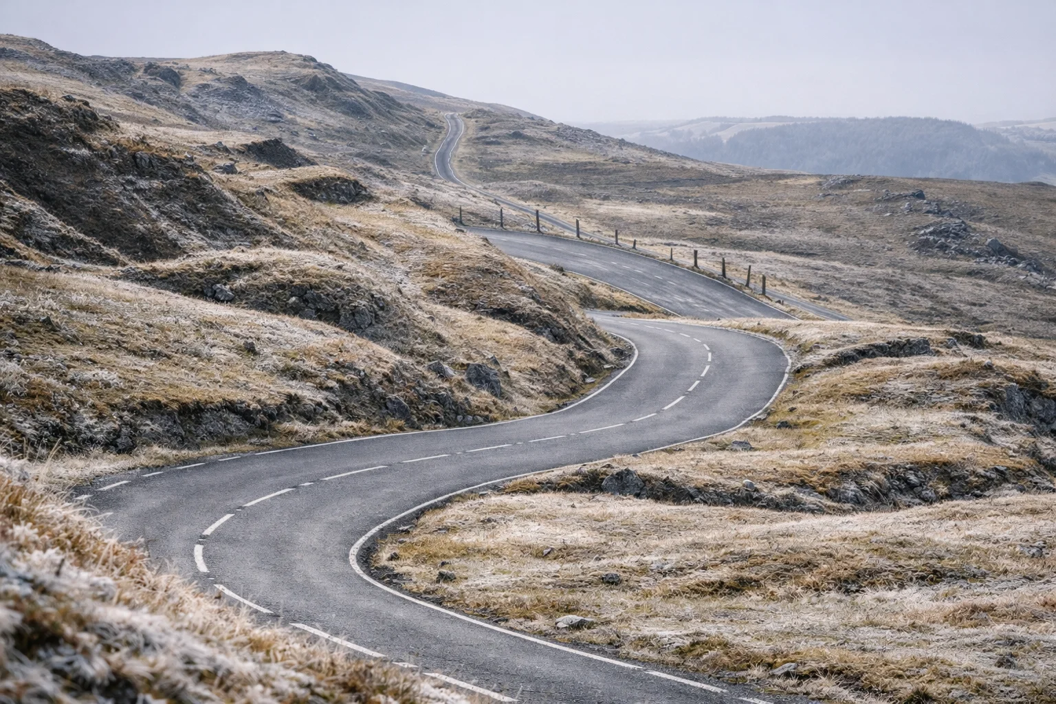 A narrow road winding across frosted open moorland in the Beacons