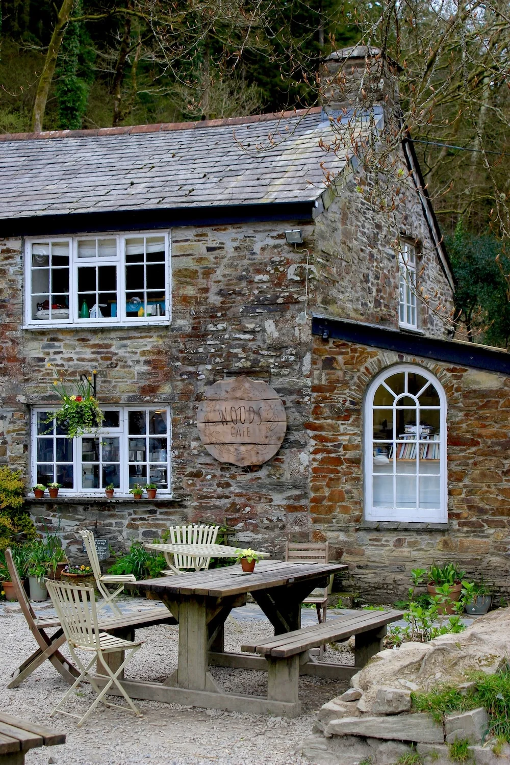 A charming stone cottage with outdoor seating in a leafy garden